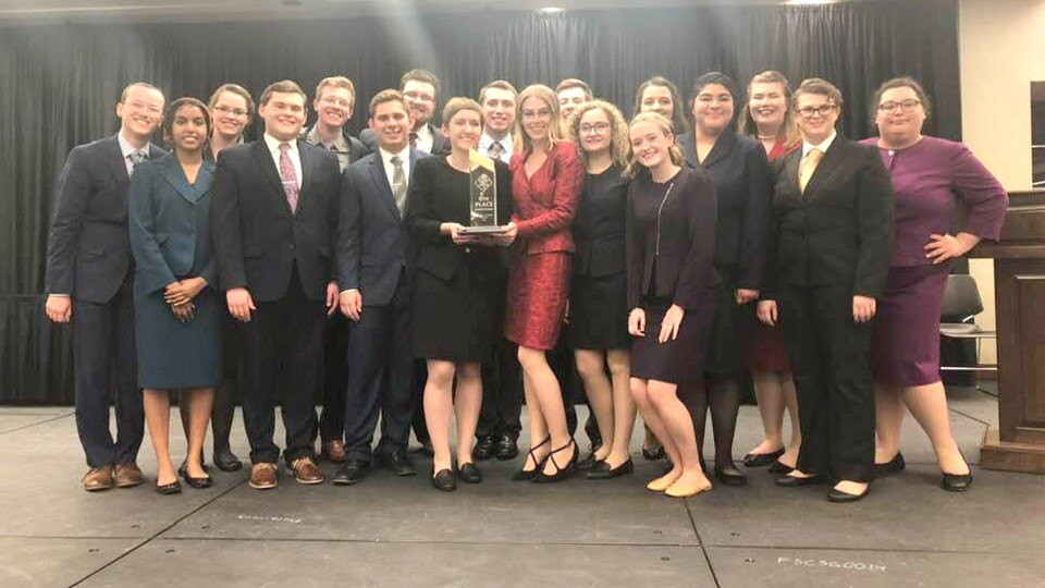 UNL competitors and Becca Human holding her trophy; links to news story