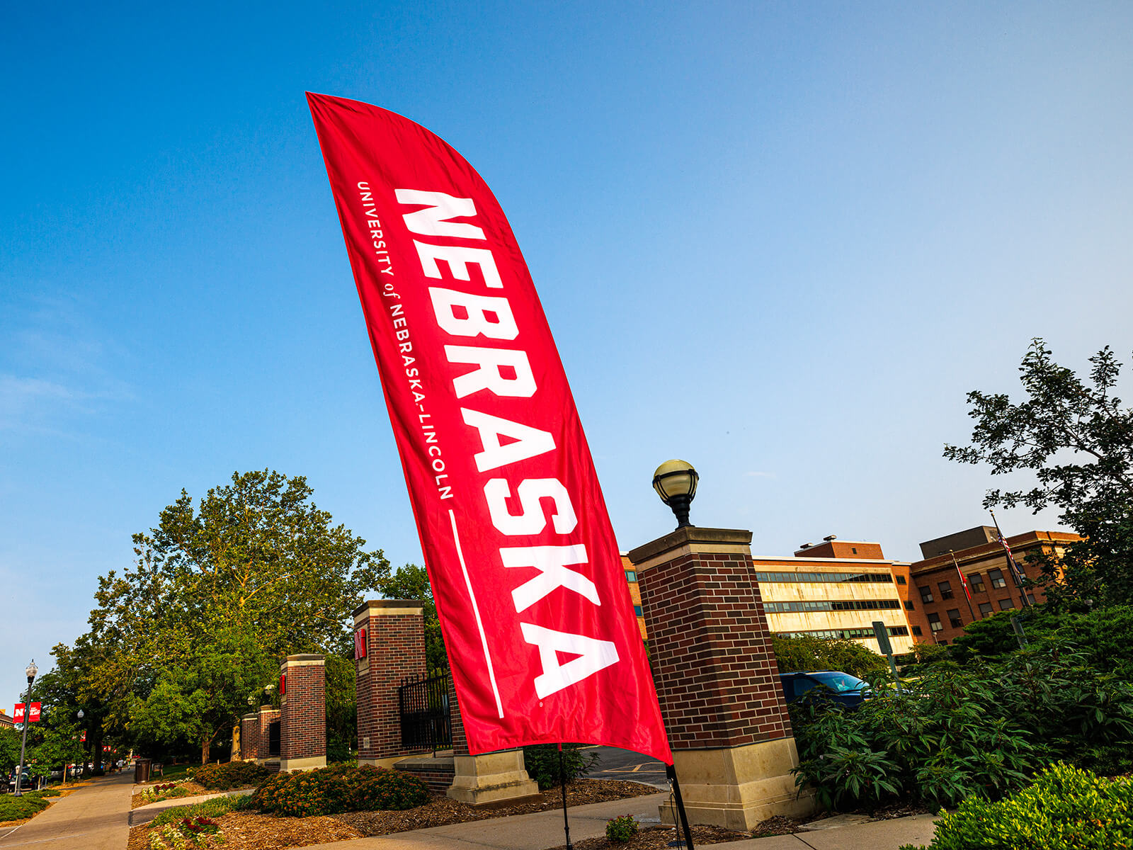 Red Nebraska banner flying by entrance to campus