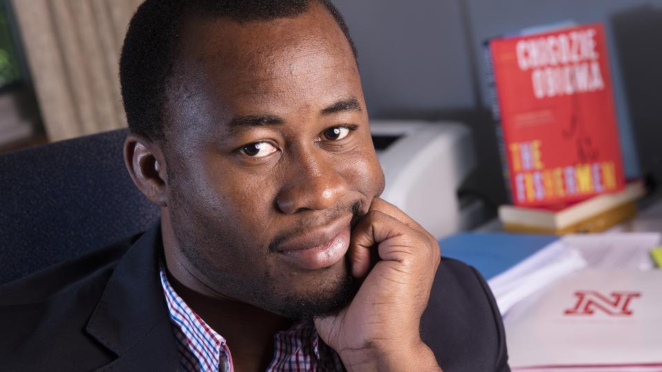 Chigozie Obioma poses with his debut novel, The Fishermen; links to news story