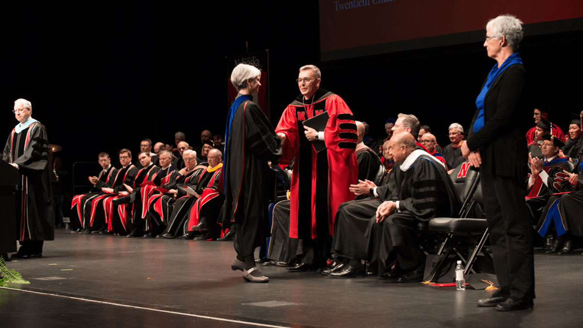 Joy Castro shakes Chancellor Ronnie Green's hand after delivering the benediction at his installation ceremony