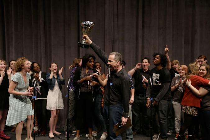 Poet Matt Mason lifts a trophy and cheers along with a crowd of high school slam poets