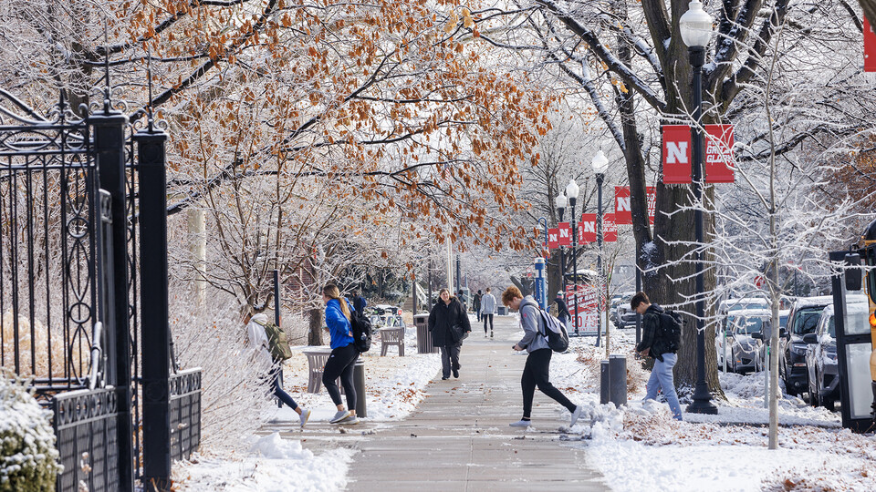 Students walk across campus on a snowy day; links to news story
