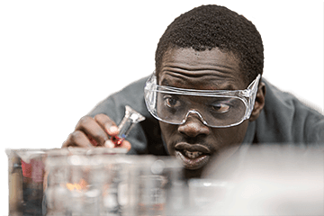 A student wearing safety goggles in a chemistry lab measures diffusion of light through colored liquids.