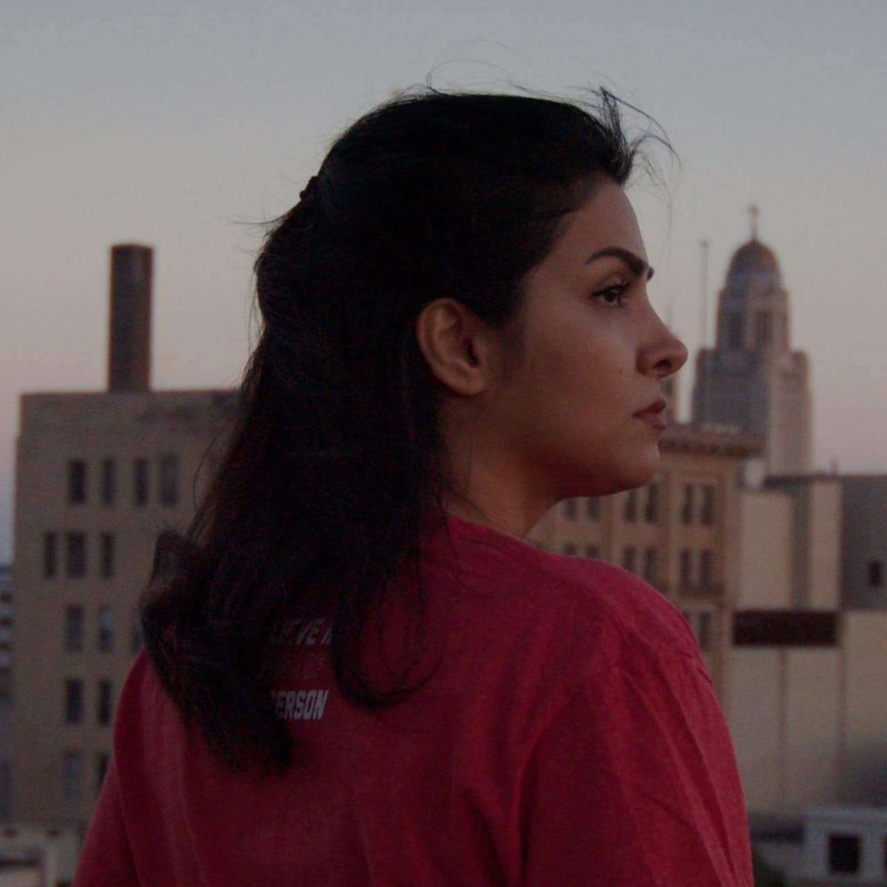 Profile of Nasrin from behind looking at the Lincoln skyline with the State Capitol in the distance