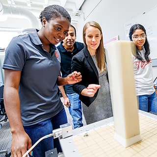 Civil engineering students and professor watch as a shake table jolts a column and its base.
