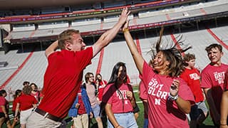 Two students high five during the Tunnel Walk and New Student Welcome events in Memorial Stadium.