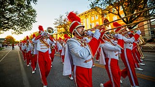 The Cornhusker Marching Band marches down R Street in the Homecoming Parade as the sun begins to set.