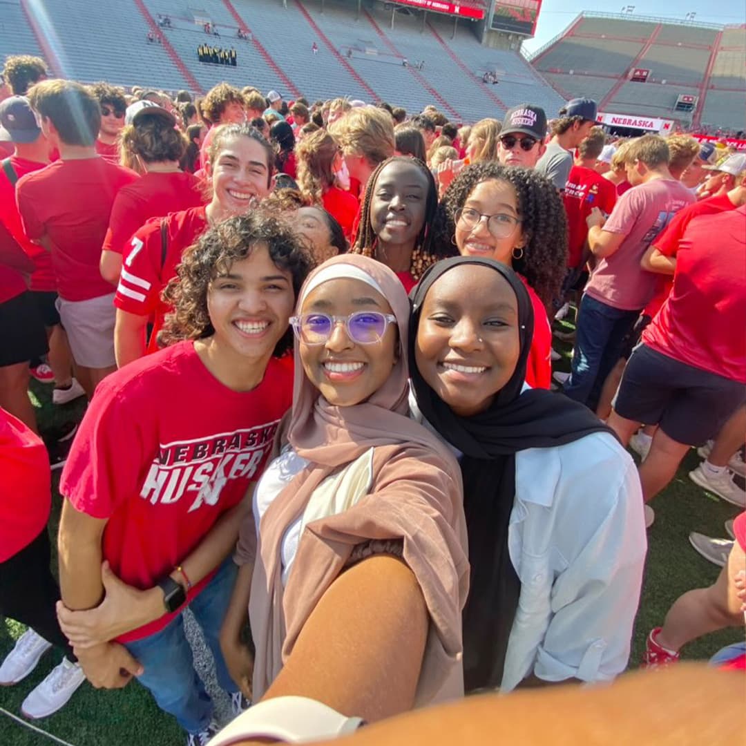 A group of students take a selfie on the field at Memorial Stadium.
