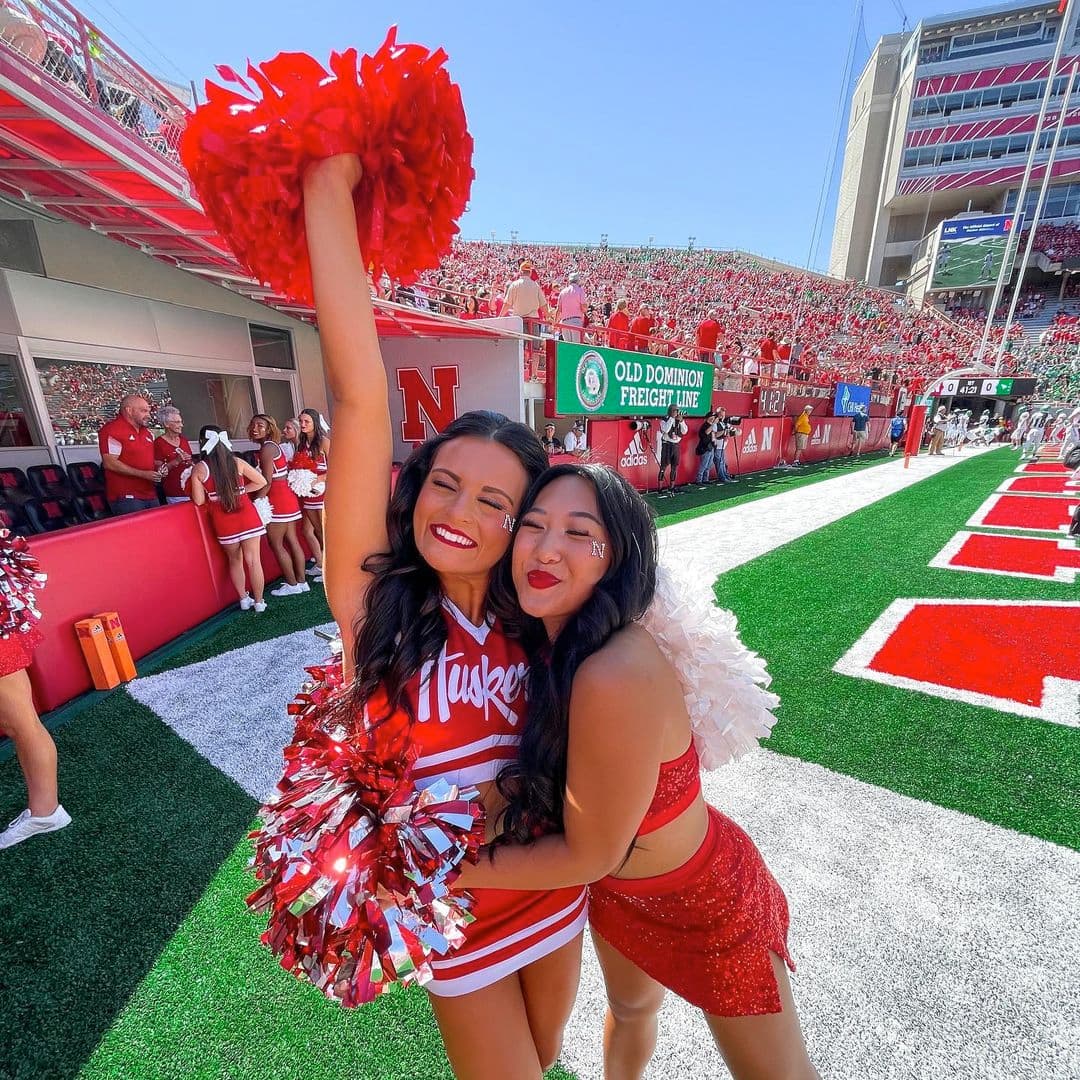 Cheerleaders pose while on the field in a packed Memorial Stadium.