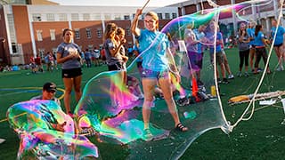 Students makes bubbles during the All-Learning Community Welcome Event on Mabel Lee Field.