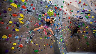 A Nebraska student clings to the bouldering wall in the Campus Recreation facility on City Campus.