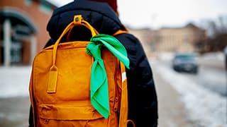 A Nebraska student wears a green bandana on her yellow backpack to show support for mental health awareness.