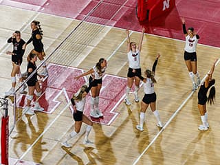 Overhead angle of the Husker volleyball team celebrating the match point in a 3-0 sweep over the U N O Mavericks.