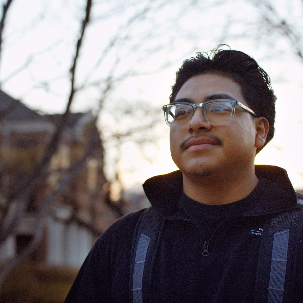 Oscar Bernabe outdoors wearing a black quarter-zip top and backpack. 