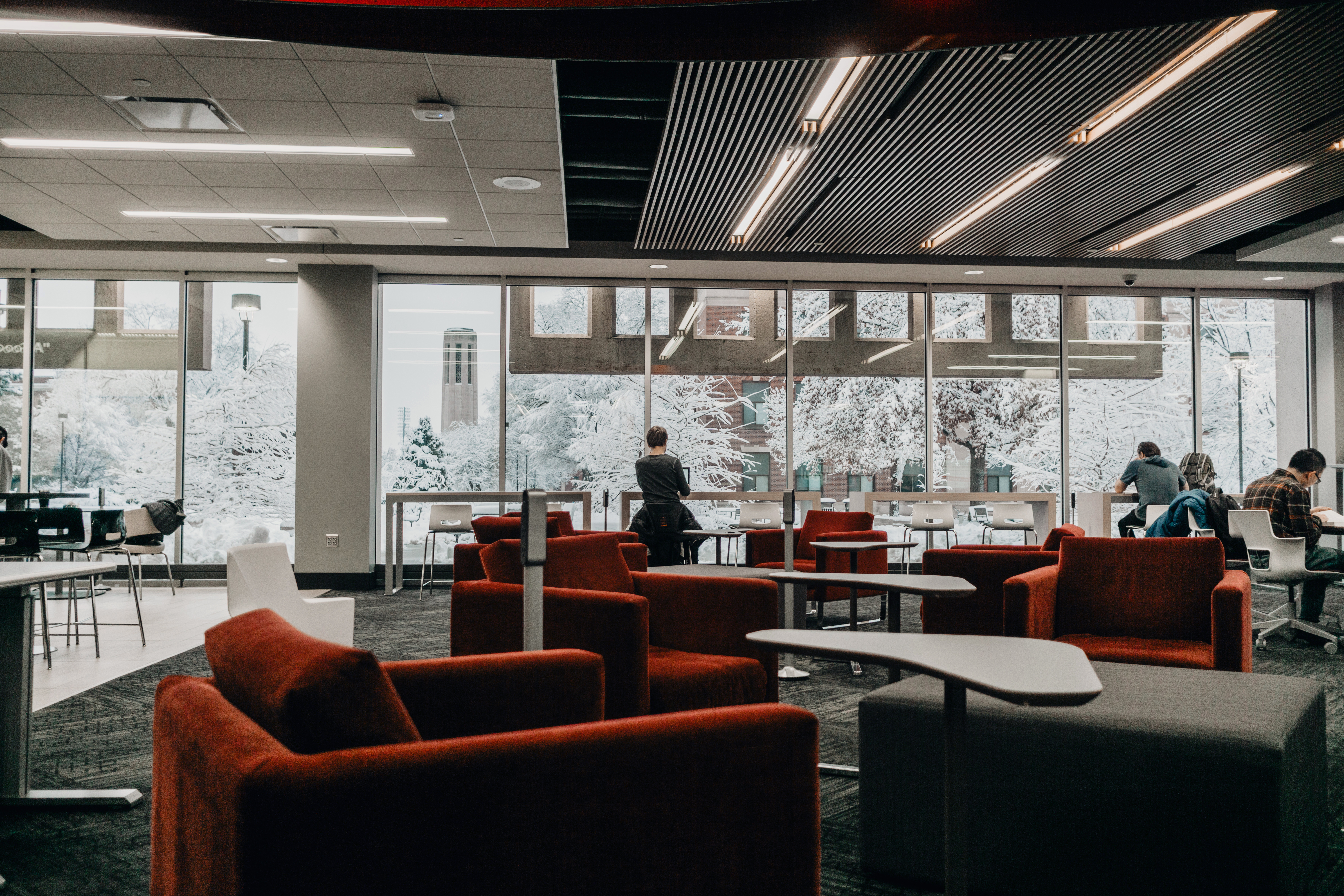 Students studying in the Adele Learning Commons look out over the snow covered campus