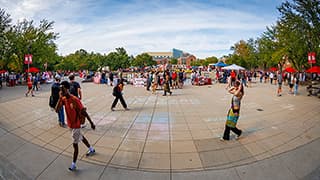 Students walk outside on the plaza north of the Nebraska Union, stopping at booths for the Nvolvement Fair for Recognized Student Organizations.
