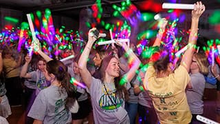 Students, waving glow sticks in the air, dance during the UNL Dance Marathon’s rave in the Nebraska Union Centennial Room.