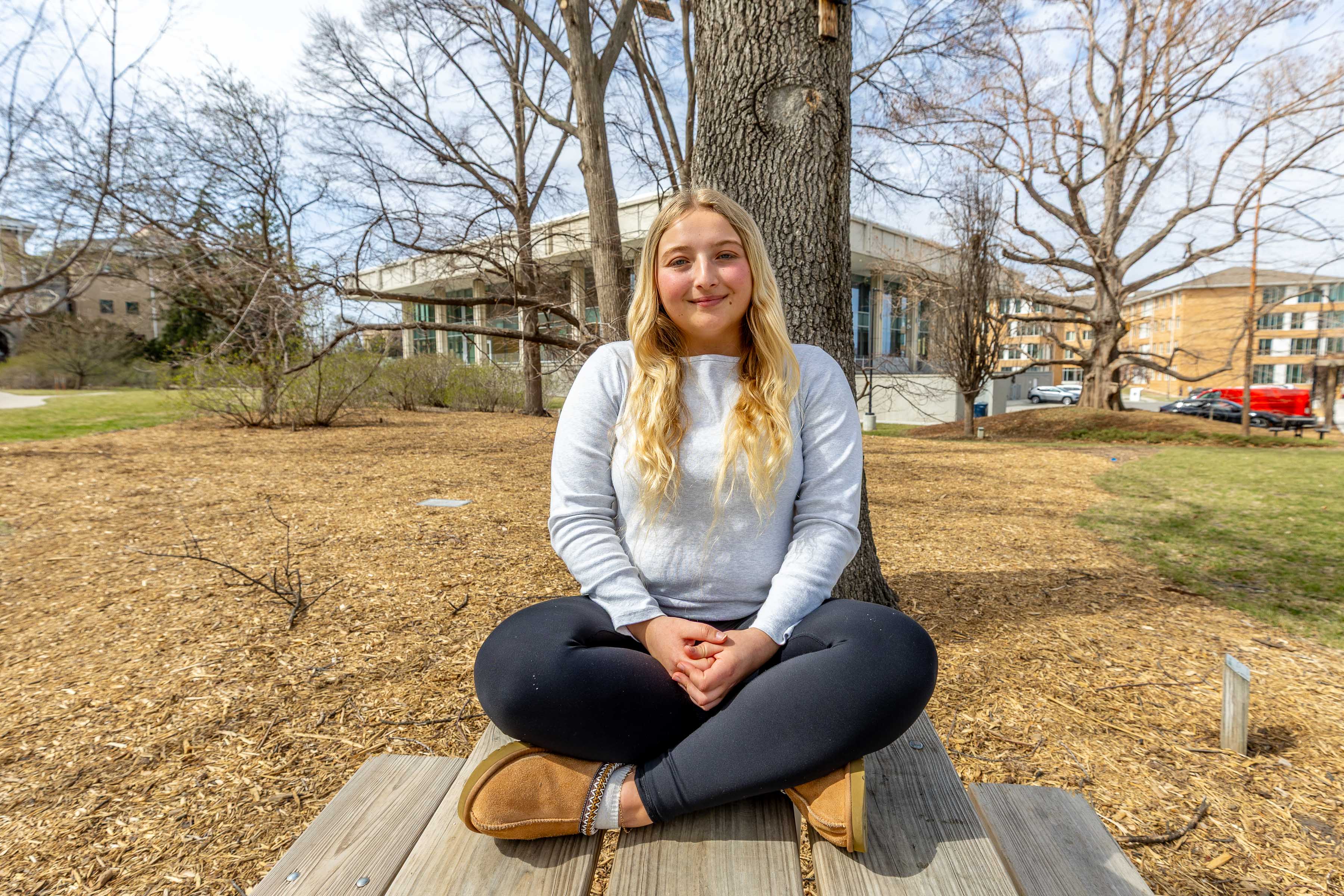 Hannah Haun sits on a bench in the Maxwell Arboretum in front of a nest box for the Southern Flying Squirrels.