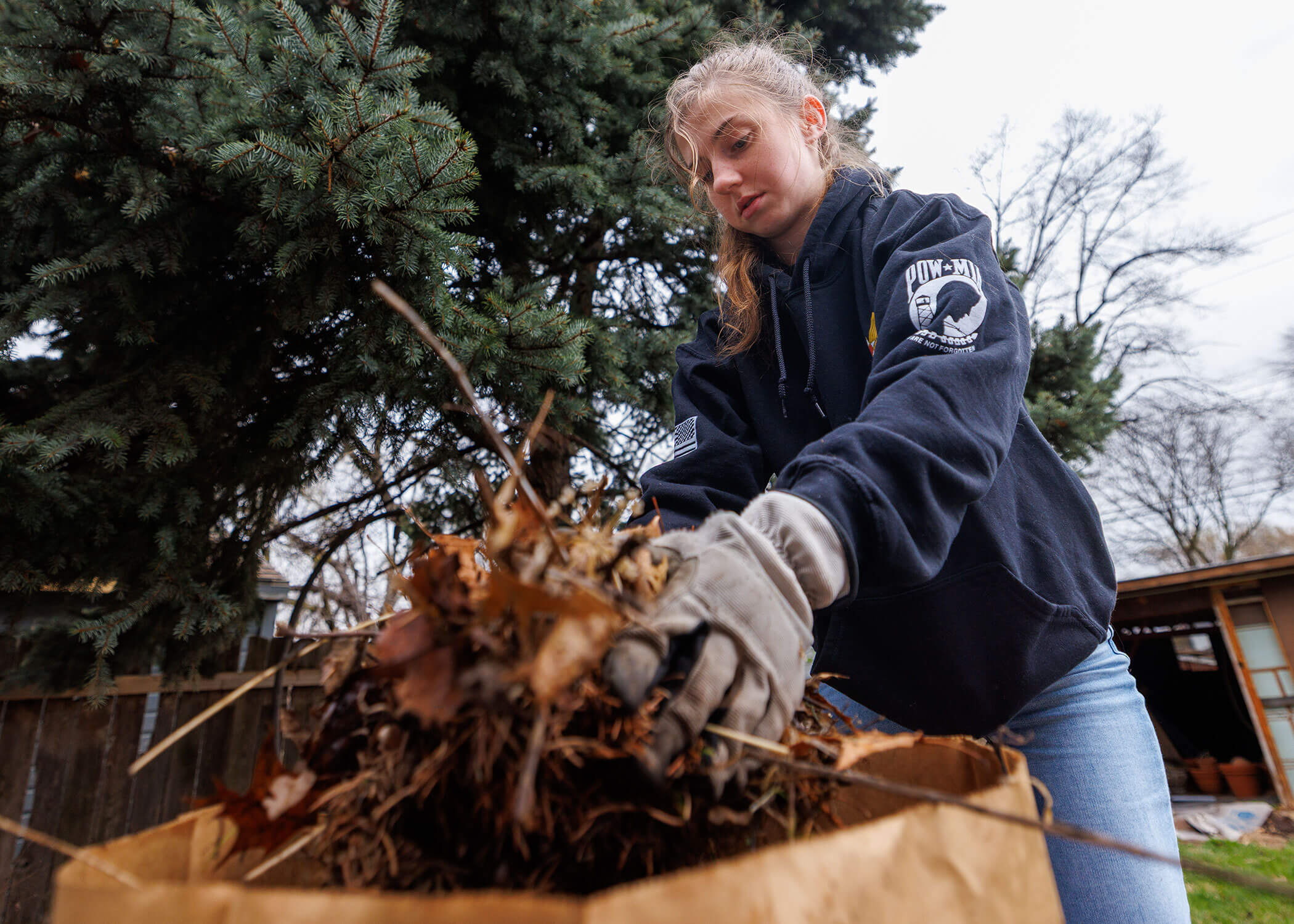 Amanda Kurinec, a senior agricultural engineering major and a member of the Arnold Air Society, places dead leaves into a bag as she helps with doing yard work. The Big Event. April 11, 2026. Photo by Jordan Opp / University Communication and Marketing