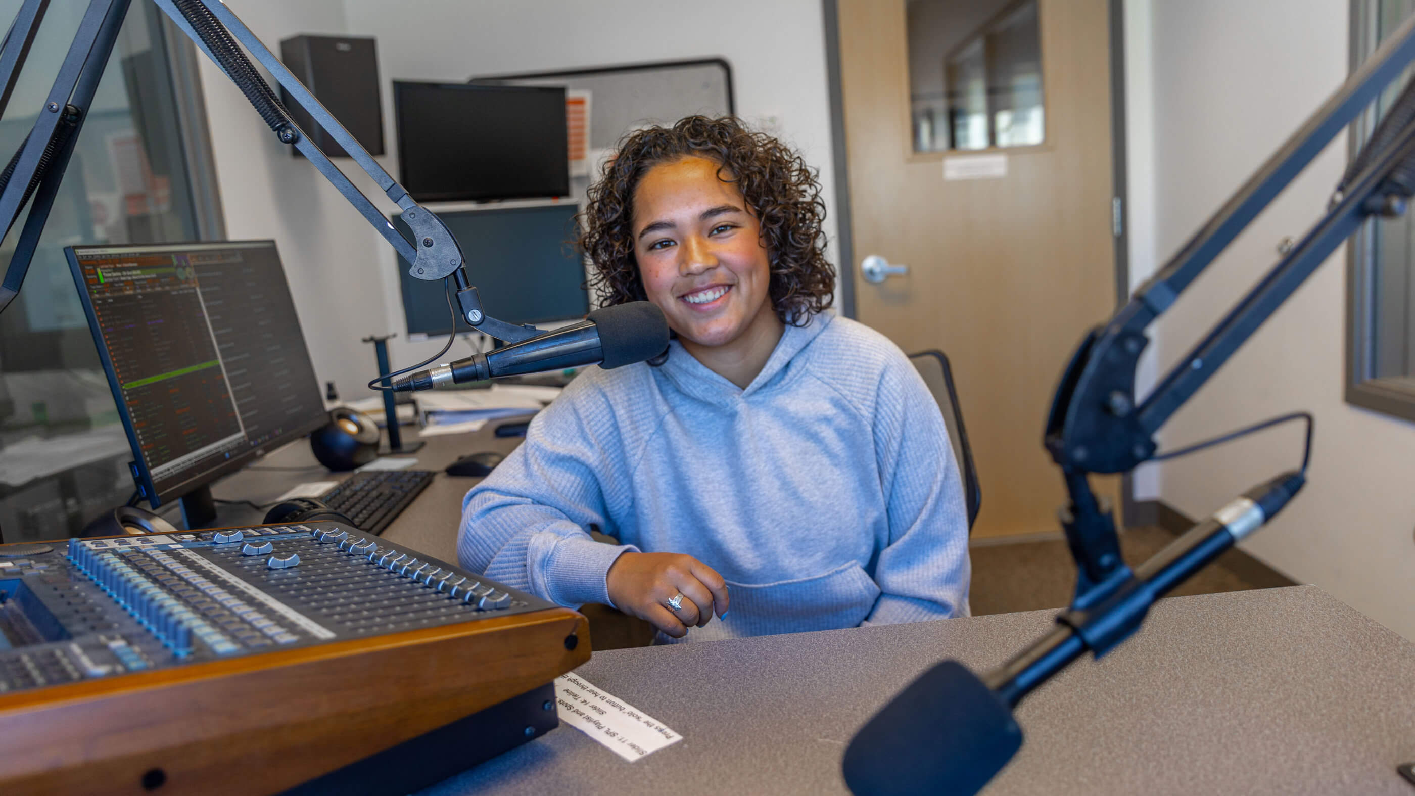 Student sitting behind mixing board in studio