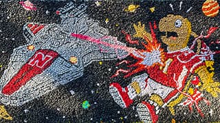Homecoming lawn decoration with spaceship with 'N' logo firing laser at cartoon turtle in a red jersey in outer space.