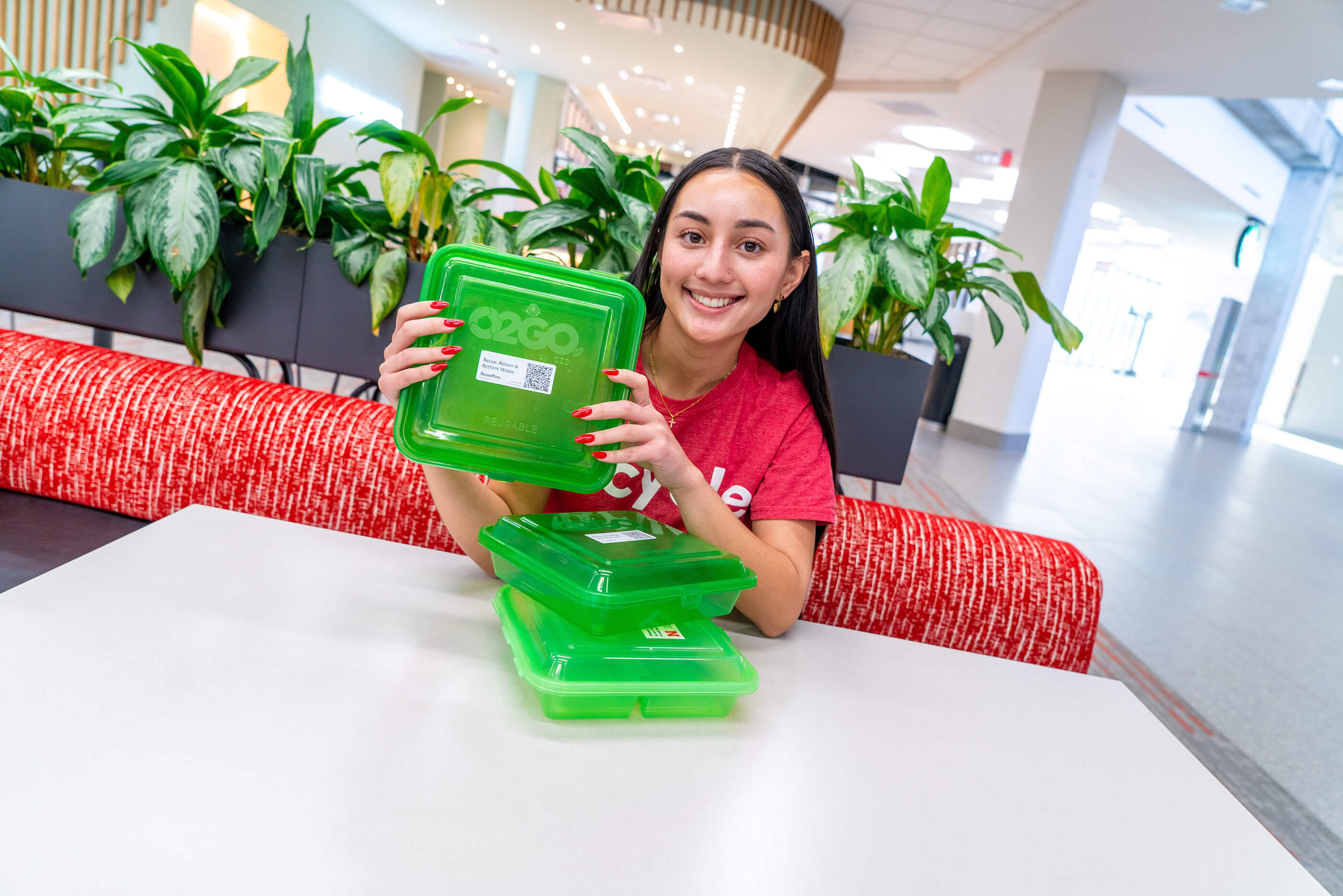 Student holding green recycled plastic storage containers