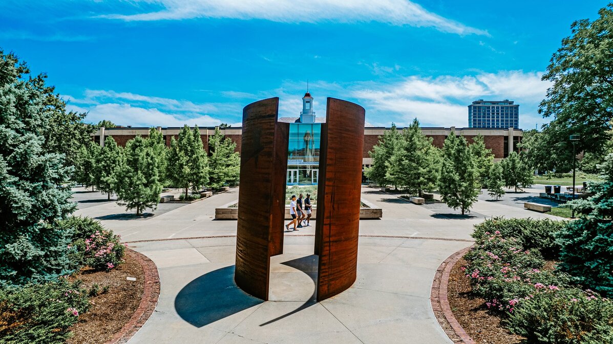 People walk past the Greenpoint sculpture on campus