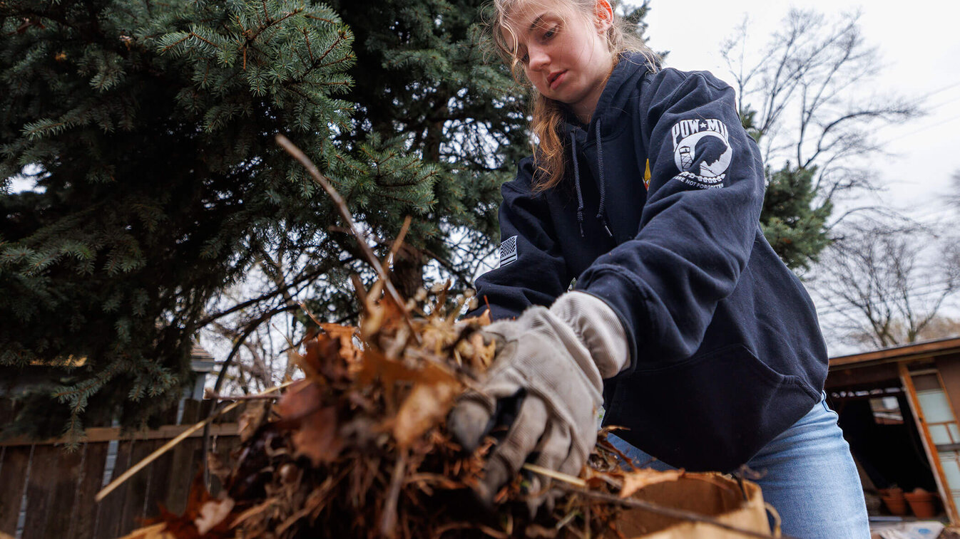 Amanda Kurinec, a senior agricultural engineering major and a member of the Arnold Air Society, places dead leaves into a bag as she helps with doing yard work. The Big Event. April 11, 2026. Photo by Jordan Opp / University Communication and Marketing