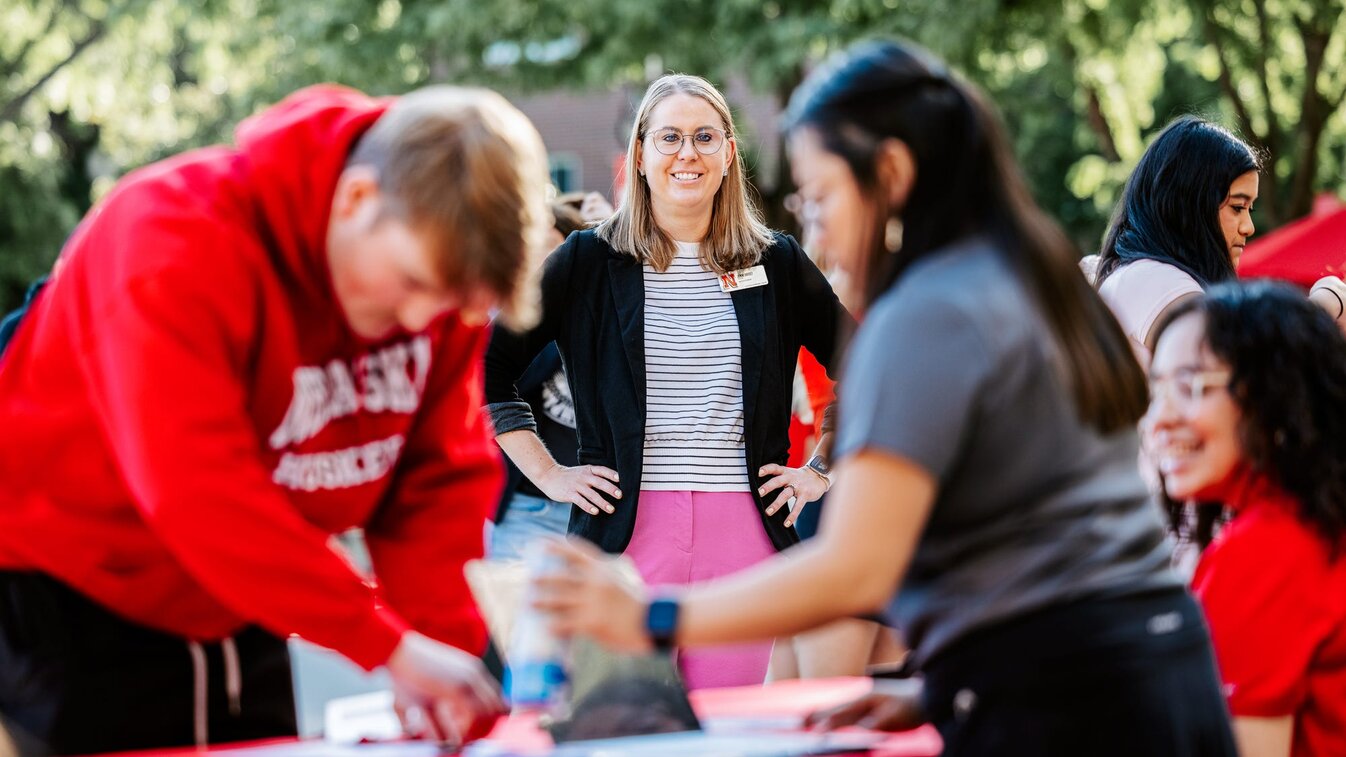 Jenni stands in the background as incoming students check in at welcome desks outside the union