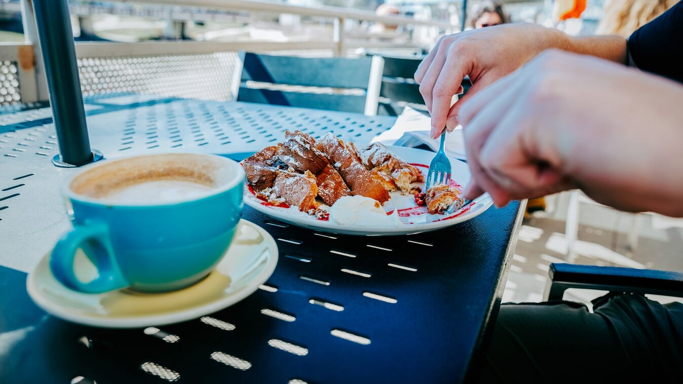 A person cuts into french toast as he sits on the patio of The Hub Cafe