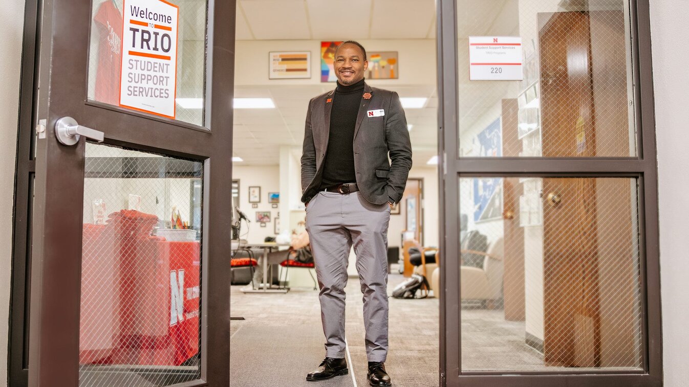 Cameron smiles for a photo at the entrance of the TRIO office