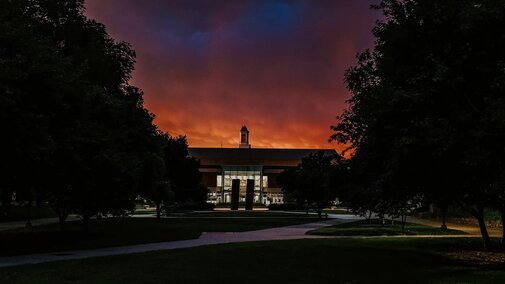 The sun rises over Love Library in the distance