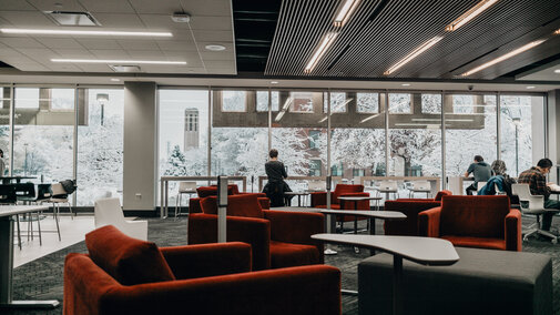 Students studying in the Adele Learning Commons look out over the snow covered campus