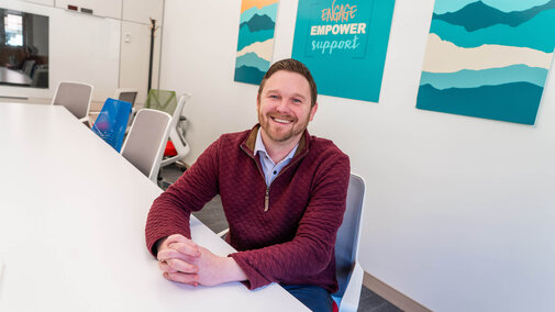 Staff member sitting at large desk with blue poster in background