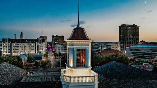 The sun sets on Lincoln with the Love Library cupola in the foreground and downtown Lincoln in the distance