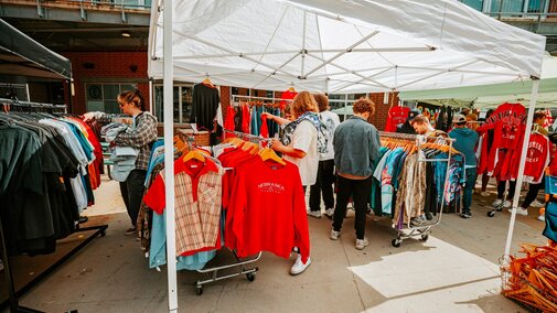 People shop at a pop-up market with secondhand Husker shirts outside in the Railyard
