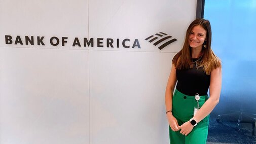 Reese smiles for a photo at the Bank of America office next to a sign with the company name
