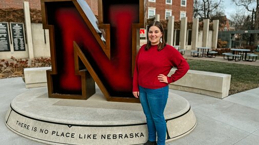 Karley smiles for a photo next to the Value of N sculpture outside the Wick Alumni Center