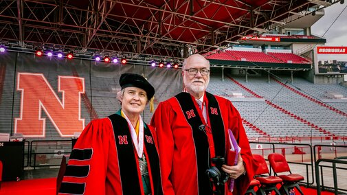 Vanessa and Bob take a photo on the stage inside the stadium ahead of undergraduate commencement