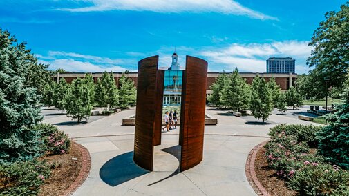 People walk past the Greenpoint sculpture on campus