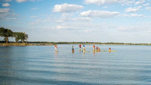 Students paddleboard on Holmes Lake on a sunny day