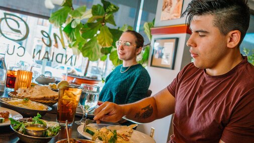 People scoop food from sharable plates at The Oven