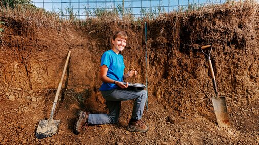 Kennadi smiles for a photo in a pit where she’s gathering samples