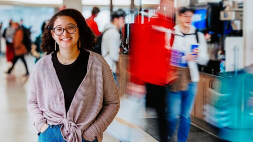 Maya smiles for a photo in Selleck Dining Hall where she and her research partner, Chloe Hoover, are surveying students about their dining habits and food sustainability