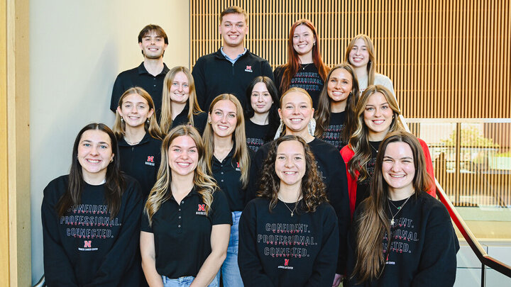 Thirteen young women and two young men — all peer career coaches in the University of Nebraska–Lincoln&#039;s College of Business, pose for a group photo on a staircase.