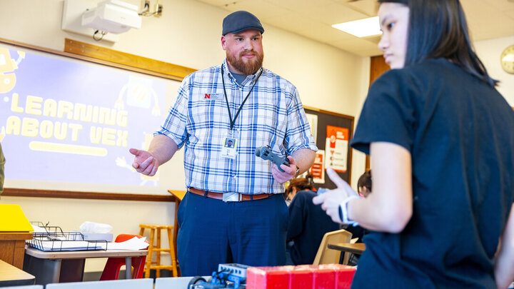 Zach Short, project director for Educational Talent Search, guides Lily Tran, a sophomore, through using the controls to make the robot move.