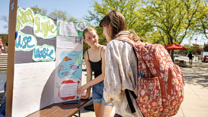 Ella Jonas (at left), a sophomore environmental and sustainability studies and political science major, invites Sophia Bartlett, a first-year student, to write what sustainability means to her during the Earthstock event celebrating Earth Day on April 22.