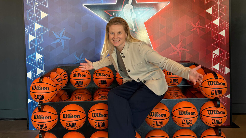 Person sitting on a couch made of NBA basketballs with a colorful star backdrop.