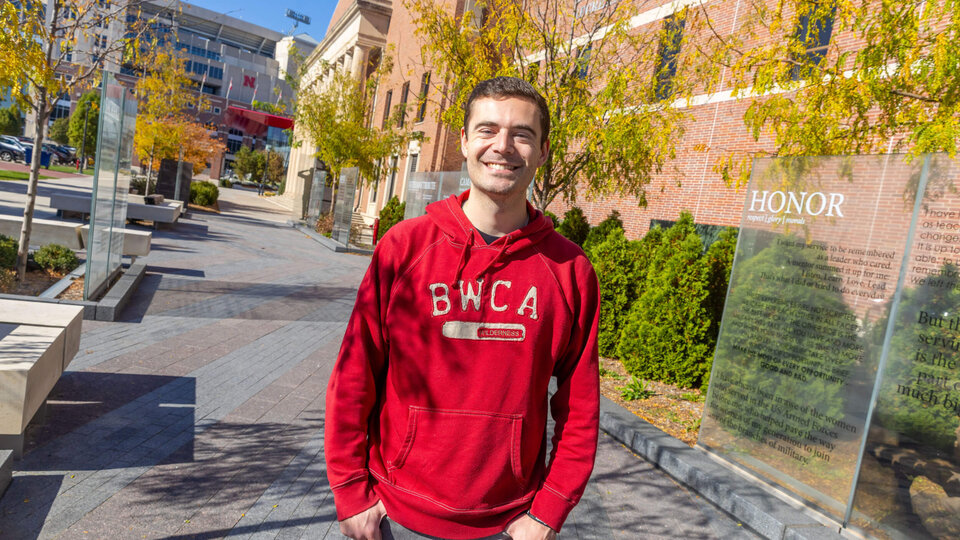Student in red sweatshirt standing by Veterans Tribute on campus
