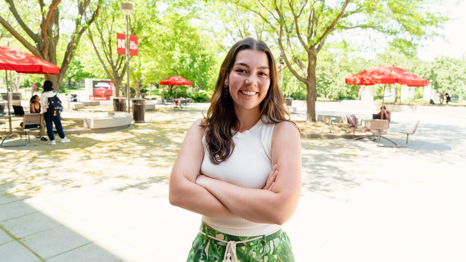 Student standing with arms crossed on plaza behind Nebraska Union